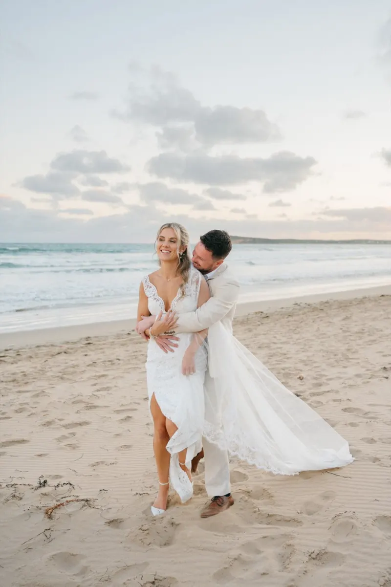 Couple embracing barefoot on the sand at dusk